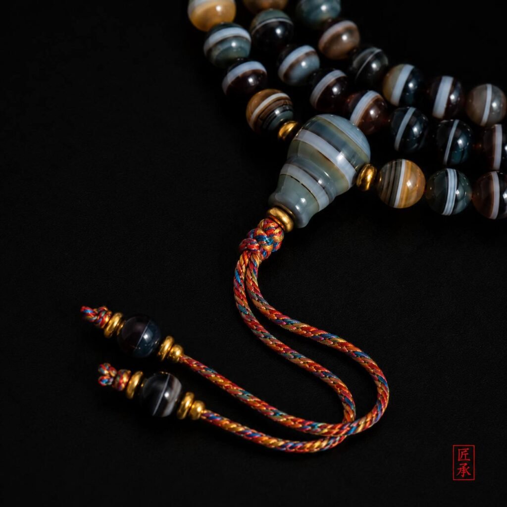 Detailed view of SHADOWED TIDES tapered focal bead and multicolored braided tassel