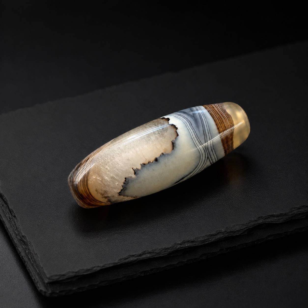 CLOUD VEIL polished agate barrel bead displayed on dark slate