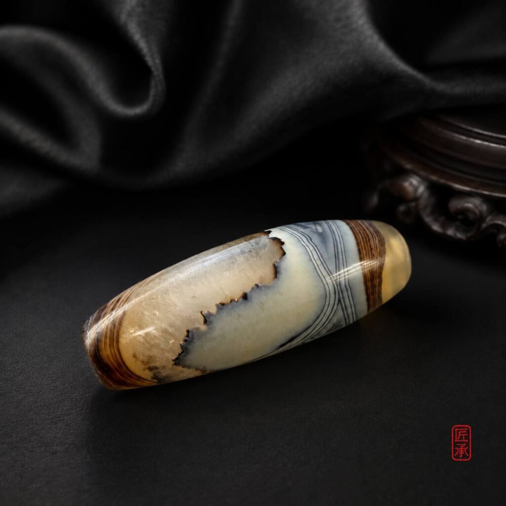 CLOUD VEIL agate barrel bead arranged with a dark textile backdrop