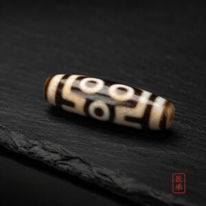 TWIN GAZE two-eye Dzi bead displayed on dark slate