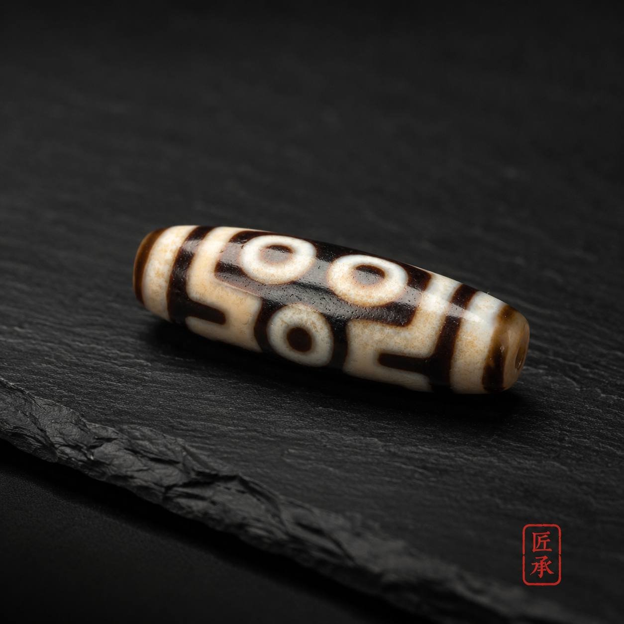 TWIN GAZE two-eye Dzi bead displayed on dark slate