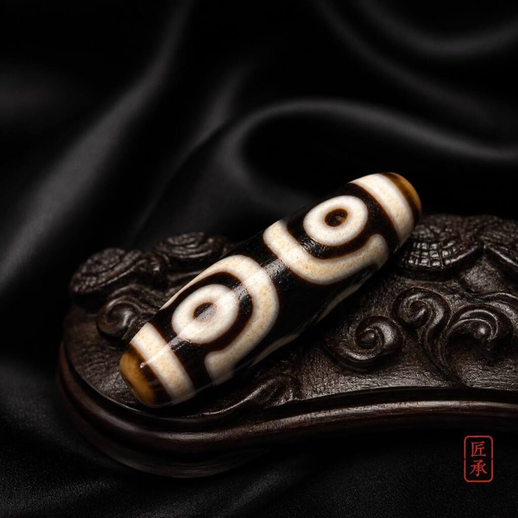 TWIN GAZE two-eye Dzi bead arranged on a carved dark display
