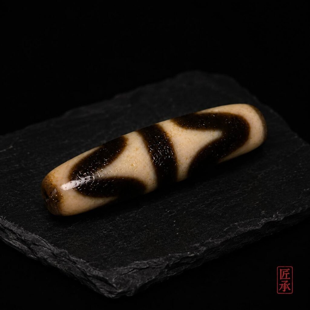 Tiger Tooth Dzi bead displayed on a dark stone surface